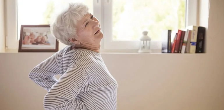 Older woman leaning back with both hands on her lower back