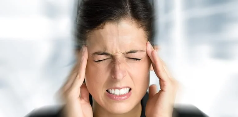 Woman gritting her teeth with her fingers pressed to her temples in a severe headache