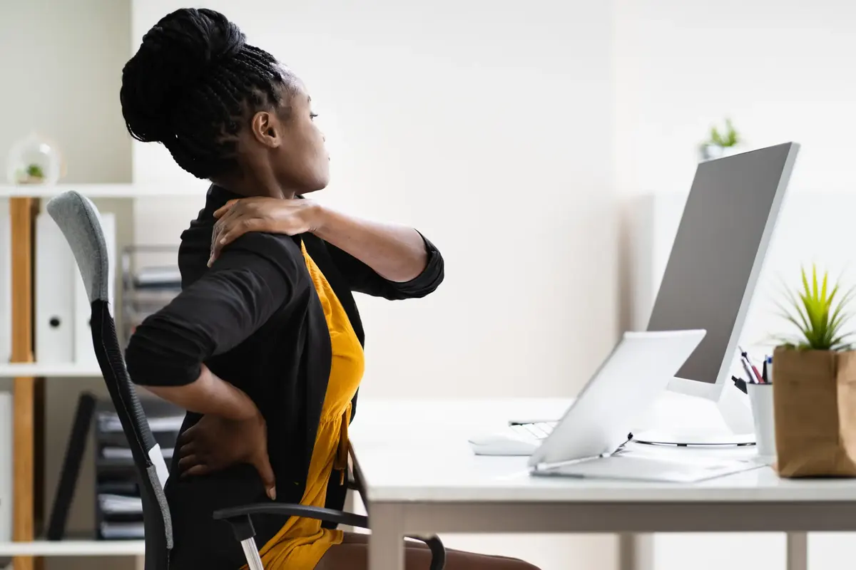 Woman at her desk holding her neck and lower back