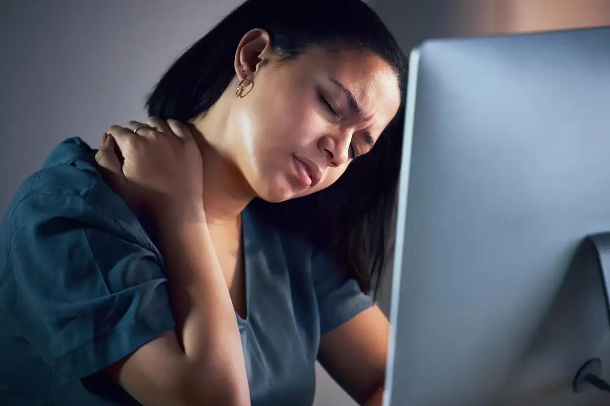 Woman at her computer holding her painful neck and shoulder